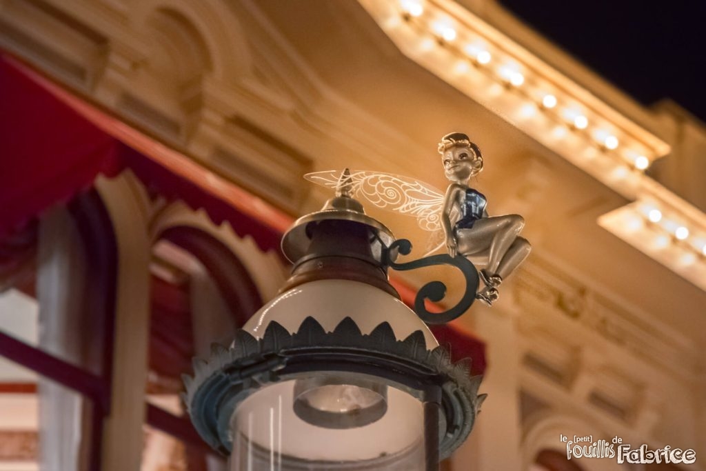 La fée Clochette assise sur un lampadaire, la nuit